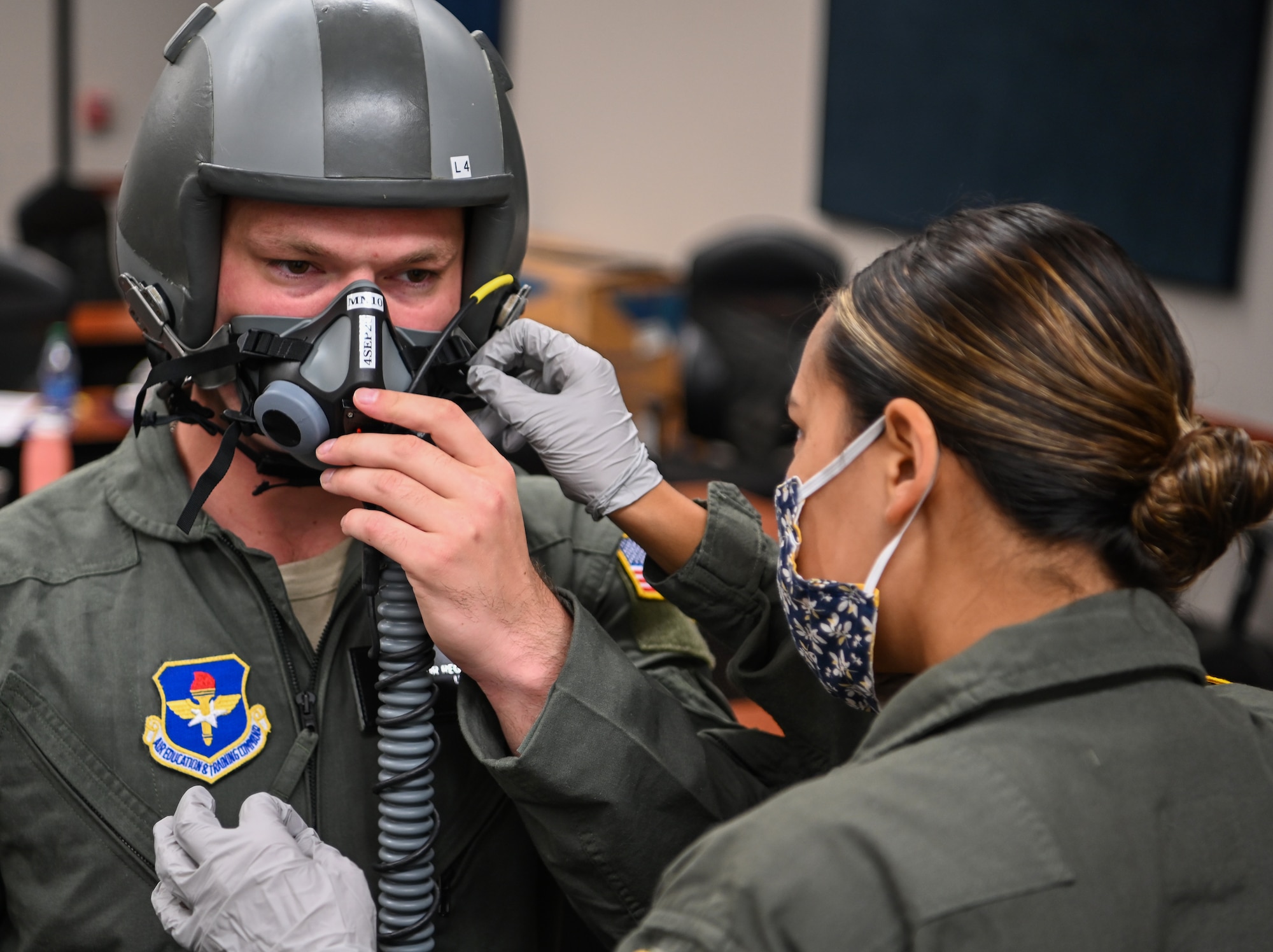 A student pilot assigned to the 23rd Flying Training Squadron at Fort Rucker, Alabama, tries on equipment, while an aerospace physiology specialist from the 14th Operational Medical Readiness Squadron makes sure the equipment fits correctly on August 21, 2020, at Columbus Air Force Base, Miss. Aerospace physiology specialists are responsible for teaching pilots and aircrews the essential skills they need to handle in-flight emergencies through various training such as aircraft pressurization, night vision, emergency first aid, oxygen equipment, physiological effects of altitude and emergency escape from aircraft. (U.S. Air Force photo by Airman 1st Class Davis Donaldson)