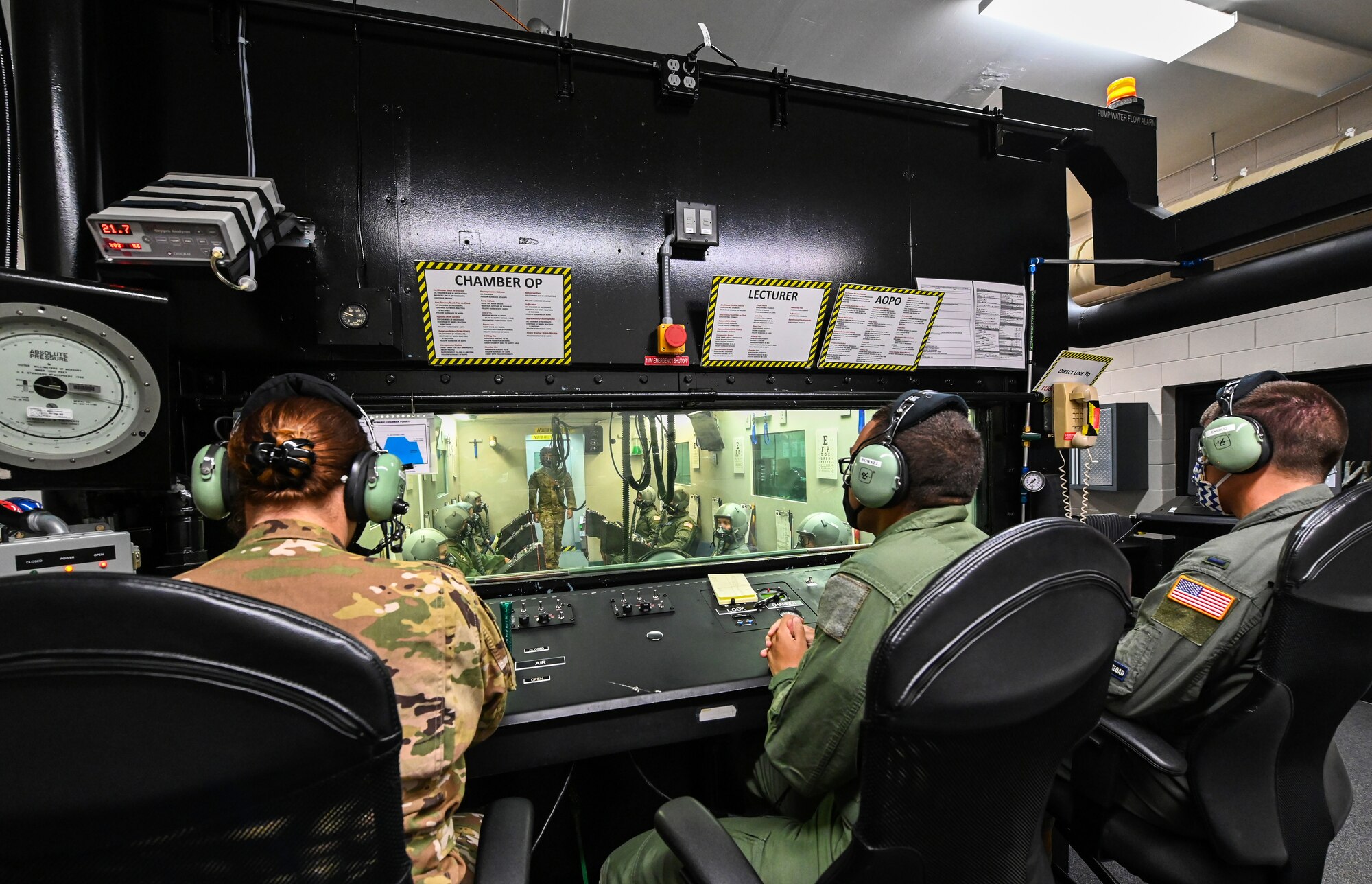 Three aerospace physiology specialists from the 14th Operational Medical Readiness Squadron observe as student pilots from the 23rd Flying Training Squadron at Fort Rucker, Alabama conduct hypobaric chamber training on August 21, 2020, at Columbus Air Force Base, Miss. The chamber provides a training system which replicates the effects of barometric pressure change on the human body. (U.S. Air Force photo by Airman 1st Class Davis Donaldson)