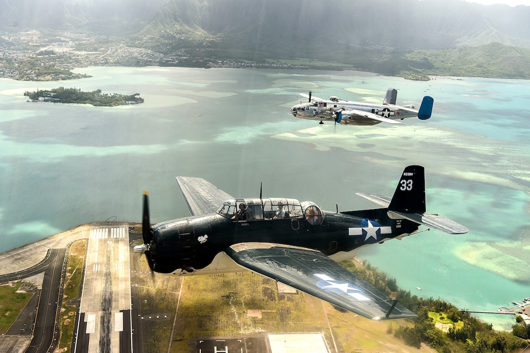 Old military airplanes fly above the Hawaiian Islands.