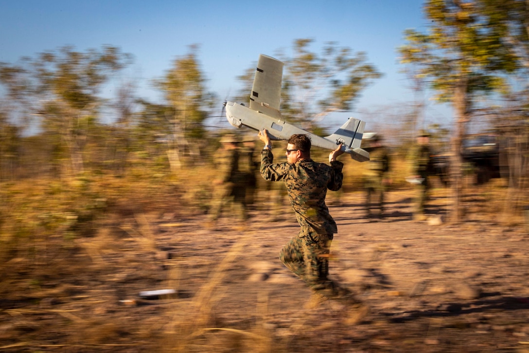 A Marine prepares to throw a small aircraft into the air.