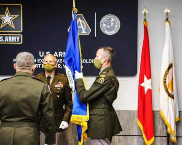 Col. Derek Bird holds the Army Acquisition Corps flag, as he is chartered as Project Manager, Soldier Survivability at Fort Belvoir, Va., August 21, 2020.