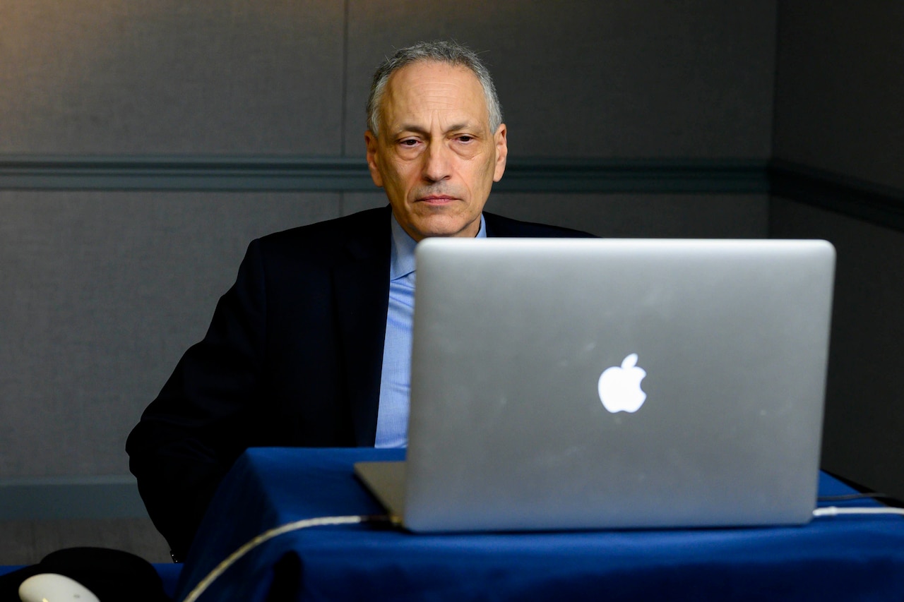 A man sits in front of a laptop.