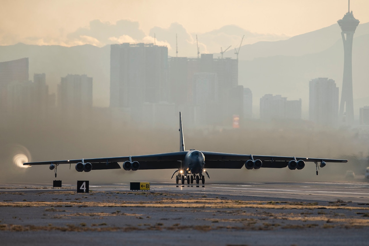 An aircraft takes off; skyscrapers can be seen in the background.