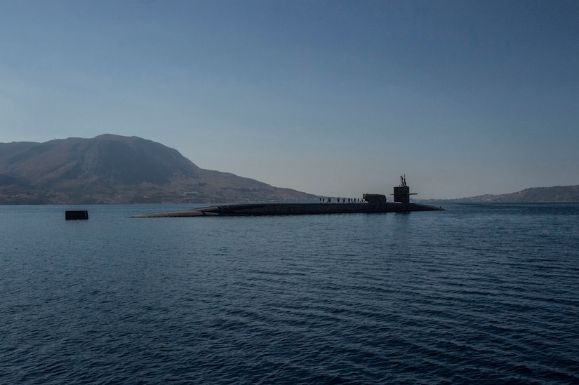 People stand atop a partially submerged submarine.