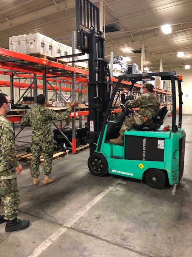 Navy Petty Officer 1st Class Jesus Martinez, left, observes as Army Staff Sgt. Derek Grudzieski guides Army Sgt. Bobby Wright in forklift operation during a mid-July annual reserve training assignment in support of the DLA Disposition Services site at Warner Robins, Georgia.