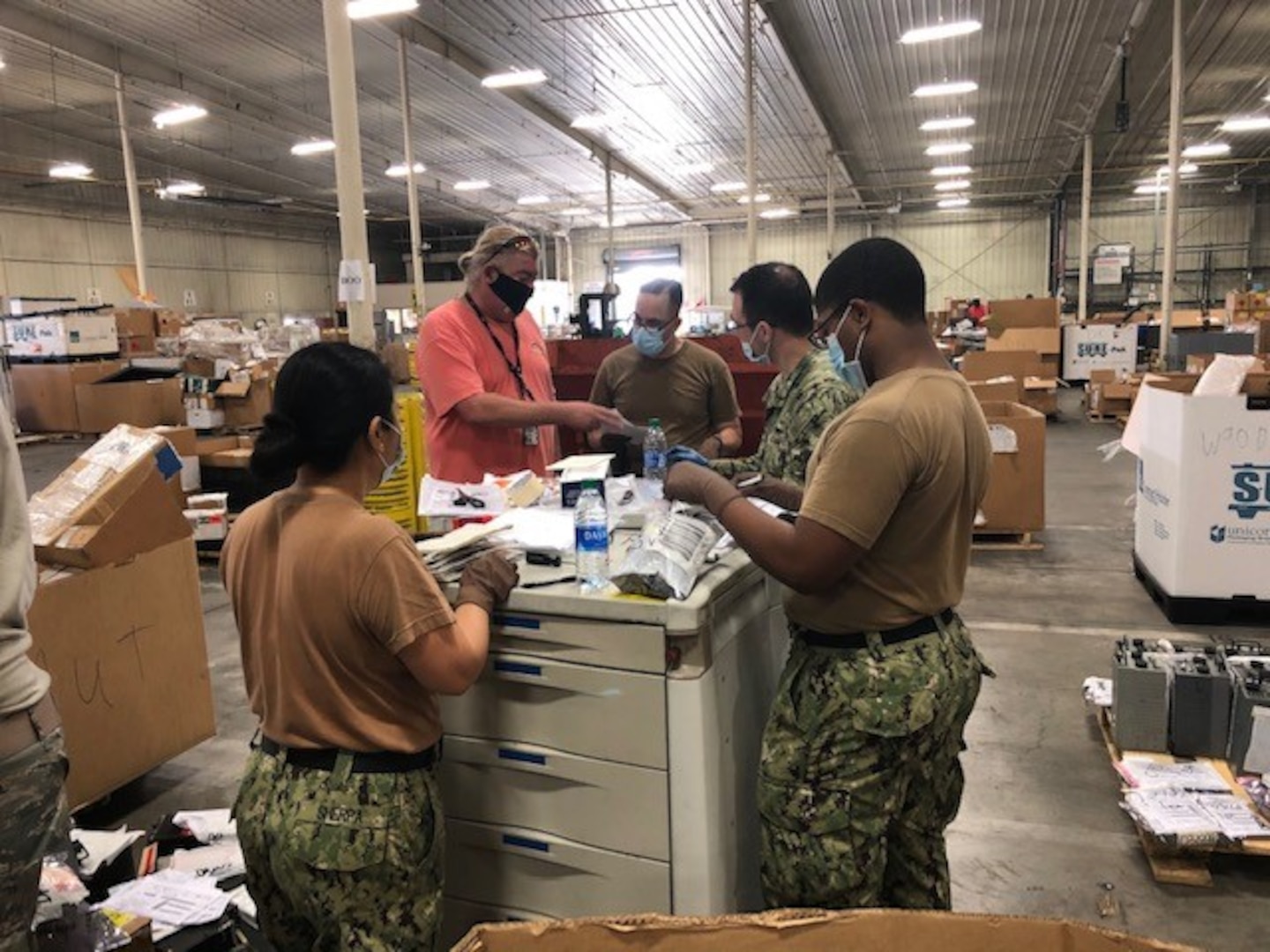 Navy Petty Officer 2nd Class Lobsang Sherpa, far left, aids DLA Disposition Services employee Thomas “CJ” Czerniejewski, along with Chief Petty Officer Cesar Acosta, Petty Officer 2nd Class Gordon Cahoone and Seaman Apprentice Joseph Deramus as they attack the backlog of received items at the DLA Disposition Services site at Warner Robins, Georgia.
