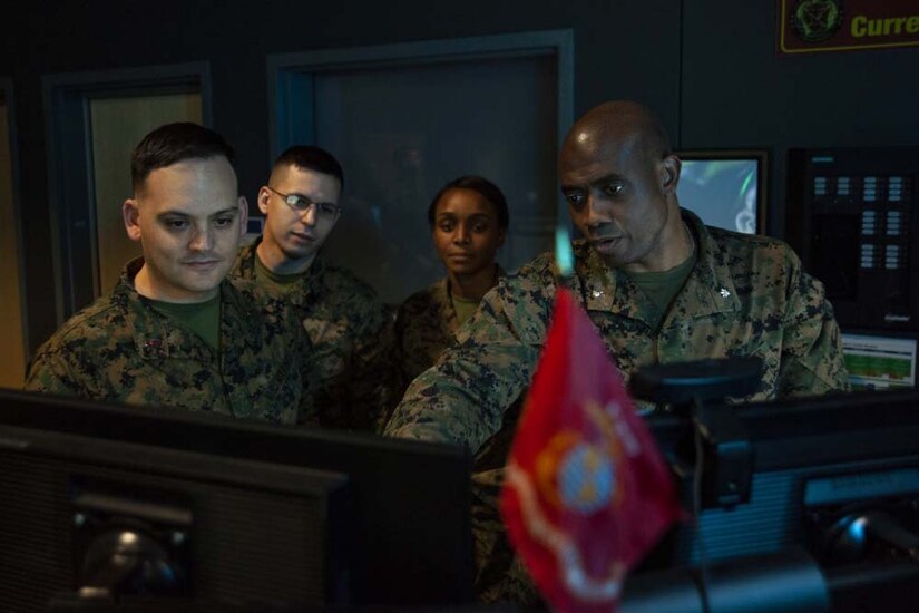 Four Marines look at a computer monitor.