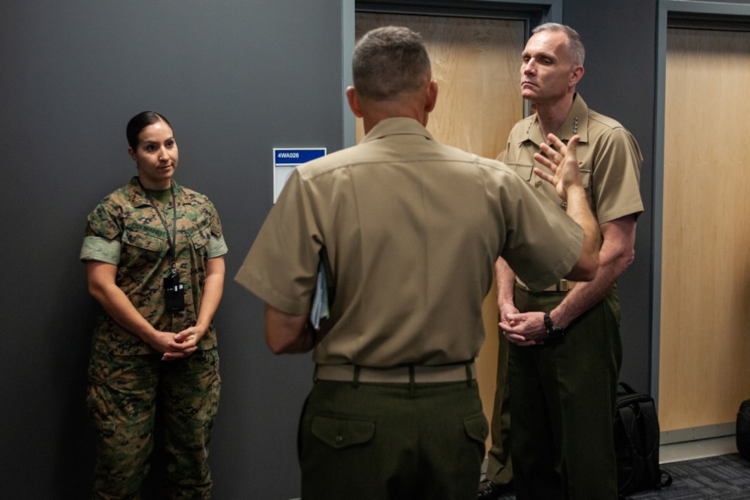 Two Marines talk to another Marine.