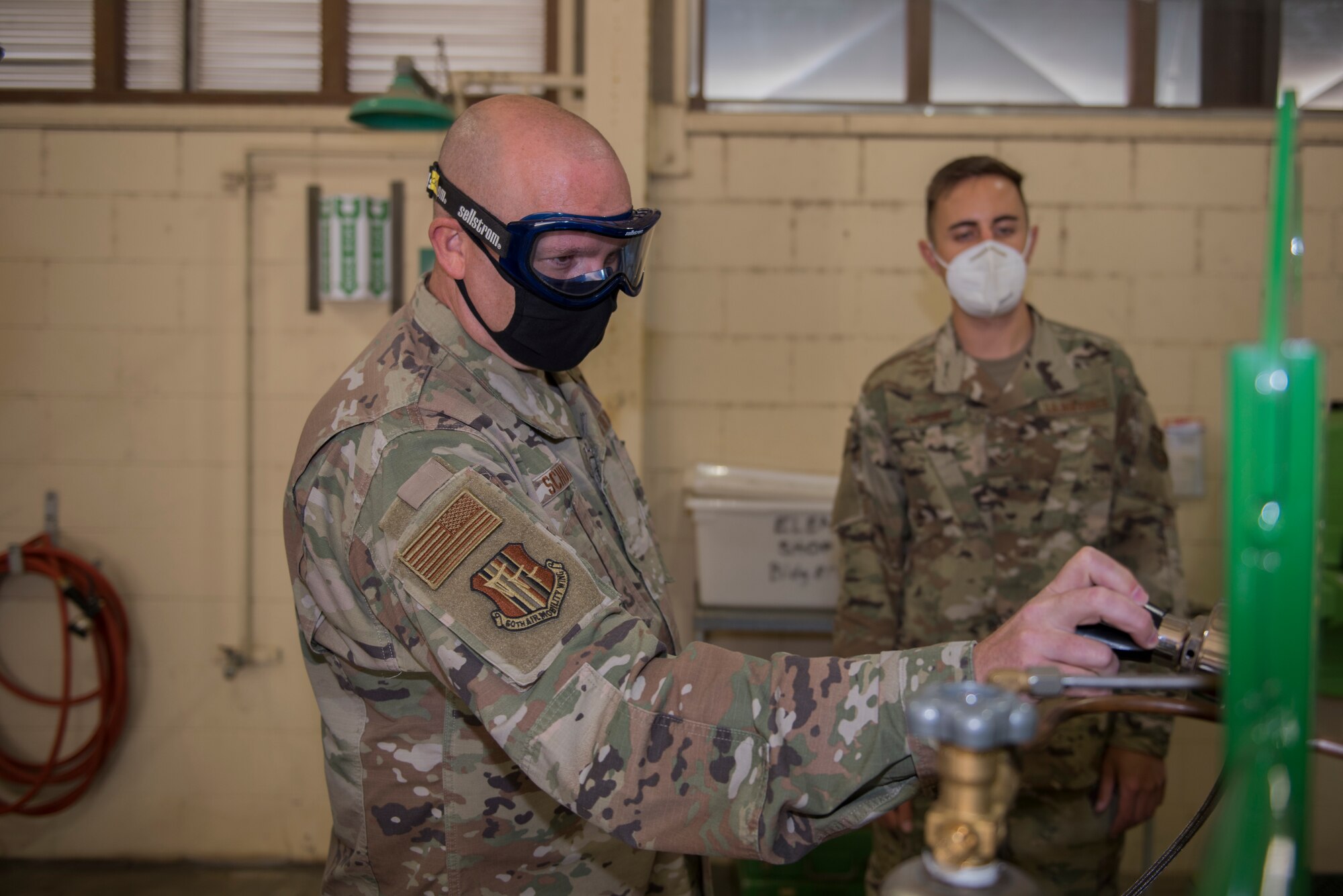 U.S. Air Force Chief Master Sgt. Robert Schultz, left, 60th Air Mobility Wing command chief, increases the pressure on a next generation patient therapeutic liquid oxygen converter while Senior Airman Peter Gatsios, 60th Maintenance Squadron aircraft electric and environmental systems journeyman, guides him during Leadership Rounds Aug. 28, 2020, at Travis Air Force Base, California. The next generation patient therapeutic liquid oxygen converter is a device used to provide medical patients who are being relocated via aircraft with oxygen during flights. The Leadership Rounds program provides 60th AMW leadership an opportunity to interact with Airmen and get a detailed view of each mission performed at Travis AFB. (U.S. Air Force photo by Senior Airman Cameron Otte)