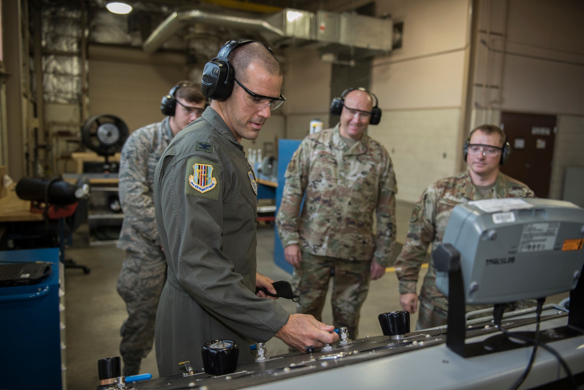 U.S. Air Force Col. Zachery Jiron, second from left, 60th Air Mobility Wing vice commander, tests the pressure on a bottle used to inflate a 25-person life raft during Leadership Rounds Aug. 28, 2020, at Travis Air Force Base, California. The Leadership Rounds program provides 60th AMW leadership an opportunity to interact with Airmen and get a detailed view of each mission performed at Travis AFB. (U.S. Air Force photo by Senior Airman Cameron Otte)
