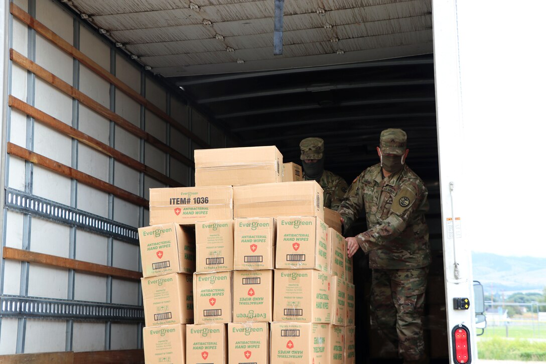 Soldiers unload boxes from a truck.