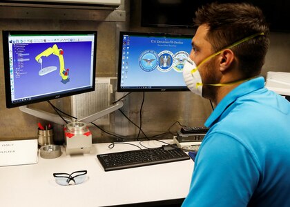 Machinist Sean Schuffert programs the robotic arm utilized in the cold spray repair.