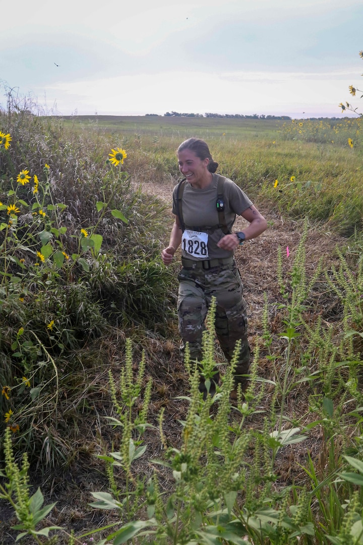 Sgt. Ayrin Hammer-Ripperger, Iowa Army National Guard, runs through brush and wildflowers, Aug. 30, 2020, at the Greenlief Training Site, near Hastings, Nebraska, during the inaugural All Guard Endurance Team time trials.