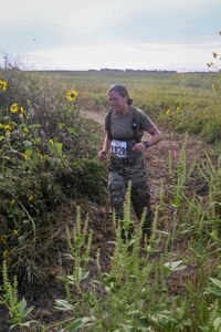 Sgt. Ayrin Hammer-Ripperger, Iowa Army National Guard, runs through brush and wildflowers, Aug. 30, 2020, at the Greenlief Training Site, near Hastings, Nebraska, during the inaugural All Guard Endurance Team time trials.