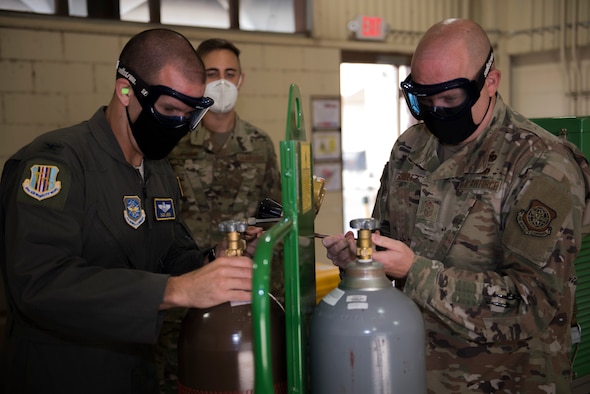 U.S. Air Force Col. Zachery Jiron, left, 60th Air Mobility Wing vice commander, and Chief Master Sgt. Robert Schultz, right, 60th AMW command chief, remove the caps off liquid oxygen bottles while Senior Airman Peter Gatsios, 60th Maintenance Squadron aircraft electric and environmental systems journeyman, guides them during Leadership Rounds Aug. 28, 2020, at Travis Air Force Base, California. The Leadership Rounds program provides 60th AMW leadership an opportunity to interact with Airmen and get a detailed view of each mission performed at Travis AFB. (U.S. Air Force photo by Senior Airman Cameron Otte)