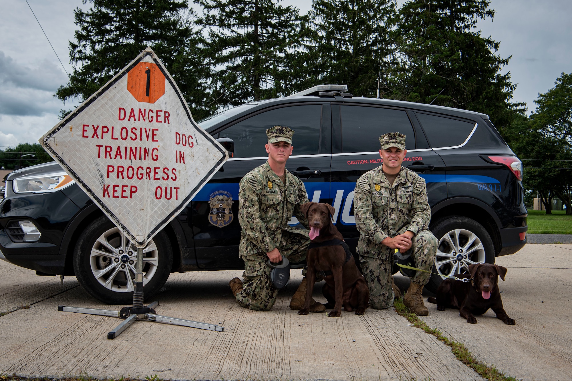 Photo of two sailors posing with dogs.