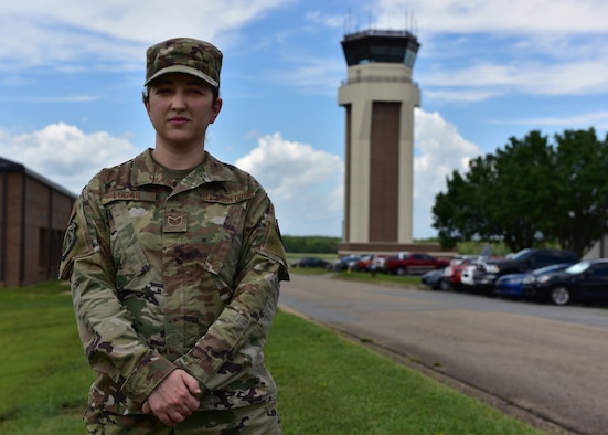 A woman in the operational camouflage pattern uniform stands in front of a tower.