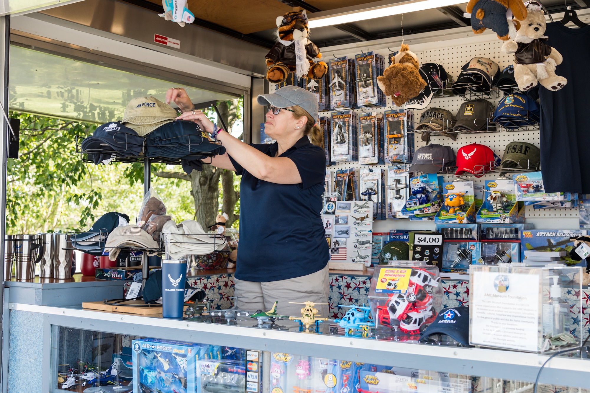 Air Mobility Command Museum volunteer Patty Coffman arranges hats in the mobile museum store trailer, Sept. 3, 2020, at AMC Museum on Dover Air Force Base, Delaware. The gift store is open outside in a mobile trailer located at the main display area. Social distancing markings are in place to help mitigate the spread of COVID-19. (U.S. Air Force photo by Roland Balik)