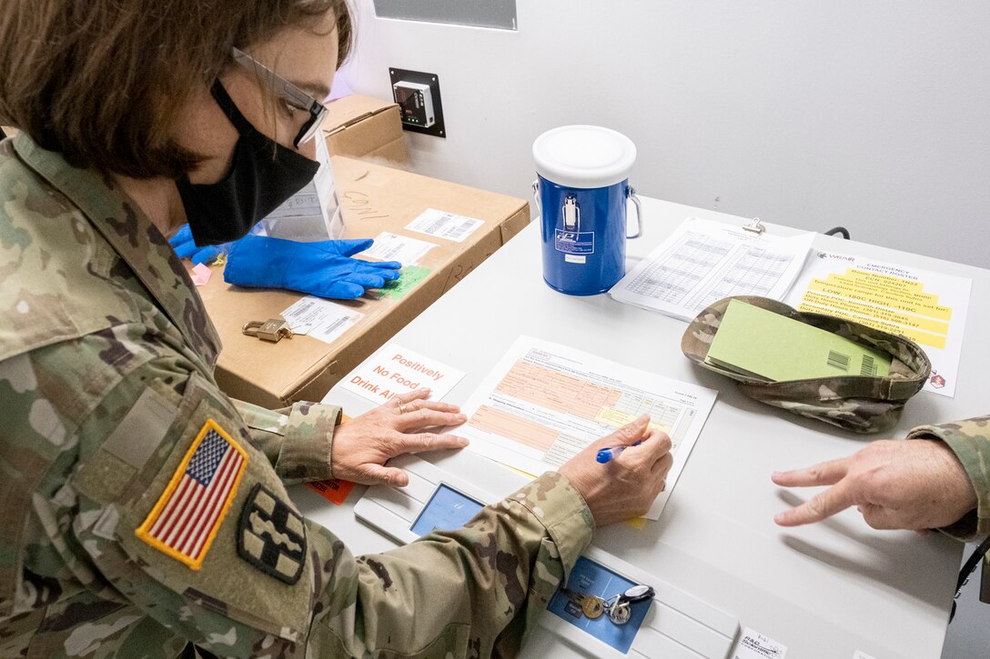 A soldier wearing protective gear signs documents.