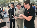 ance Brahosky, NSWC PHD’s deputy technical director, takes the controls of a student-built robot at the Oct. 16, 2019 ceremony at Oxnard College celebrating NSWC PHD, NAWC WD and NAVFAC EXWC’s receipt of grant funds from the Navy’s Office of Secretary of Defense. Much like this year’s recent disbursement, the grant money went to local students for participation in the For Inspiration and Recognition of Science and Technology (FIRST) Robotics competitions. The two students flanking Brahosky also participated in NSWC PHD’s Pre-Engineering Program.