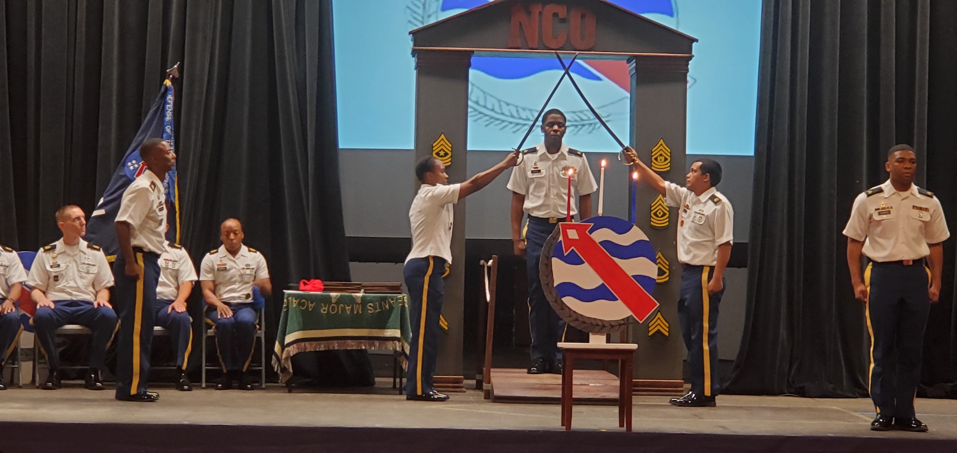 Sgt. Patric Berry, Fort Shafter Branch animal care sergeant, walks through an arch of crossed swords to officially become a member of the NCO Corps during an NCO Induction Ceremony, March 13, 2020, in the Richardson Theater on Fort Shafter, Hawaii. Historically, the NCO Induction Ceremony celebrates newly promoted Soldiers joining the ranks of the professional NCO Corps, while also building upon the pride all members share. (Courtesy photo)