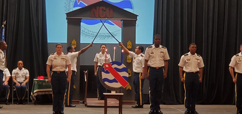 Sgt. Marissa Henson, Joint Base Pearl Harbor-Hickam Branch food inspection sergeant, walks through an arch of crossed swords to officially become a member of the NCO Corps during an NCO Induction Ceremony, March 13, 2020, in the Richardson Theater on Fort Shafter, Hawaii. Public Healthy Activity – Hawaii held their first ever NCO Induction Ceremony in conjunction with Headquarters and Headquarters Battalion. During the ceremony Soldiers received a signed Charge to the NCO, the NCO Creed, and the 2020 NCO Guide. (Courtesy photo)