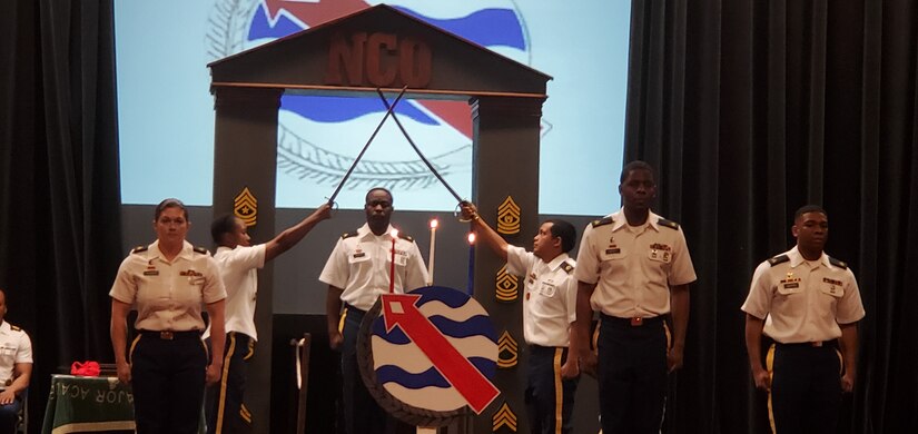 Sgt. Garry Sutton, Schofield Barracks Branch food inspection sergeant, walks through an arch of crossed swords to officially become a member of the NCO Corps during an NCO Induction Ceremony, March 13, 2020, in the Richardson Theater on Fort Shafter, Hawaii. Public Healthy Activity – Hawaii held their first ever NCO Induction Ceremony in conjunction with Headquarters and Headquarters Battalion. Historically, the NCO Induction Ceremony celebrates newly promoted Soldiers joining the ranks of the professional NCO Corps, while also building upon the pride all members share. (Courtesy photo)