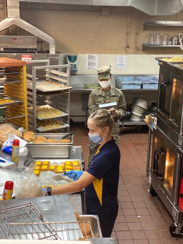 U.S. Army Spc. Regina Shillingburg, Public Health Activity-Guam veterinary food inspection specialist, is monitoring a restaurant employee preparing food at the Navy Exchange food court, Naval Base Guam, April 2020. To help mitigate the risk of COVID-19, the PHA-Guam Soldiers trained employees on sanitation measures, as well as adjusting common areas to limit customer contact. (Courtesy Photo)