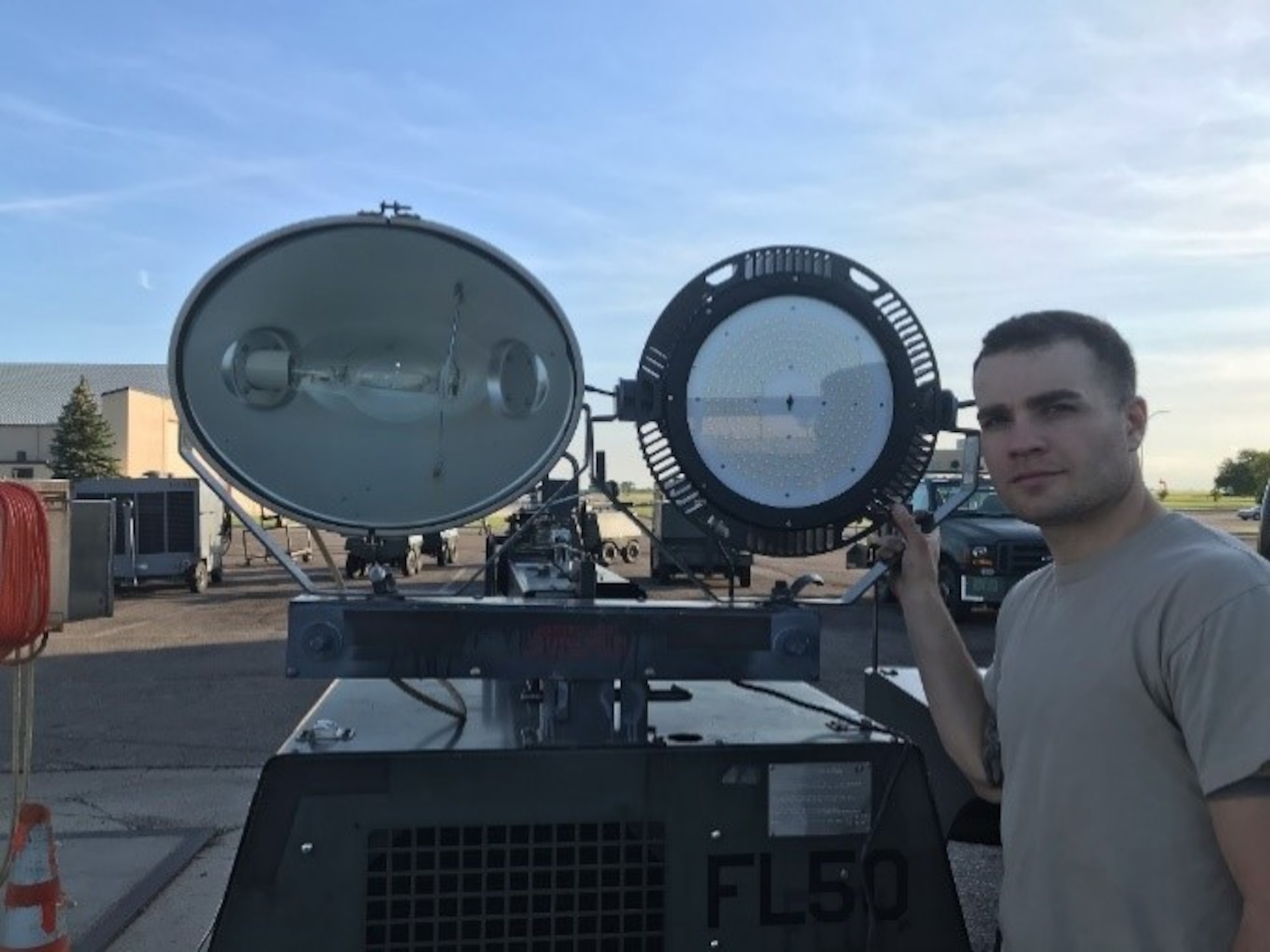Senior Airman Matthew Brown, Minot 5th Maintenance Squadron AGE Flight, compares a legacy metal-halide lamp with a new LED fixture. (U.S. Air Force photo/Master Sgt. Miguel Alvarez)
