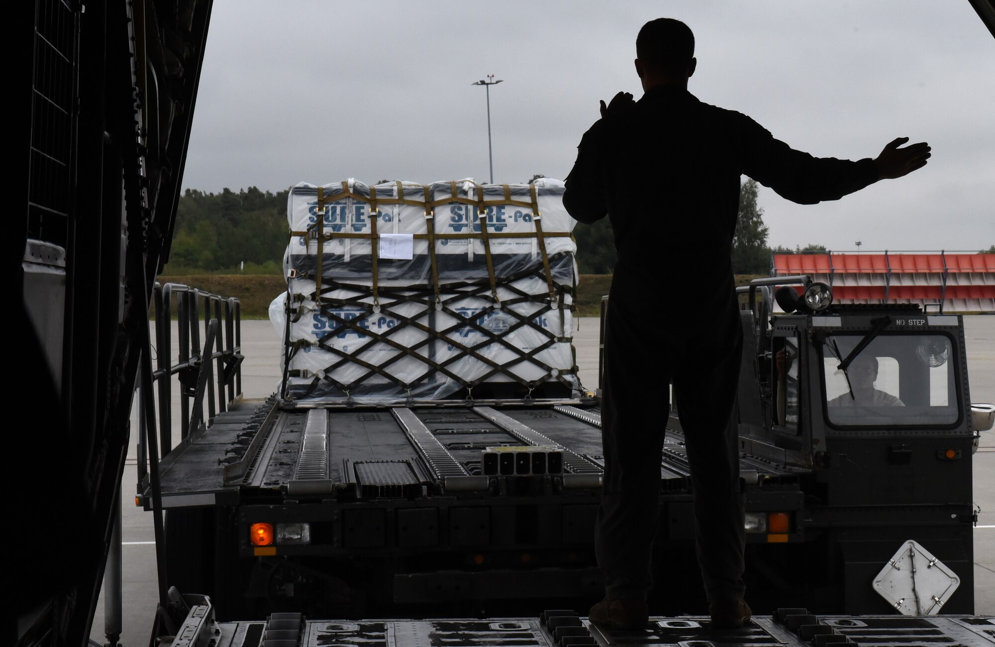U.S. Air Force Airman 1st Class Bryce James, 37th Airlift Squadron loadmaster, guides a loader with supplies toward a C-130J Super Hercules aircraft at Ramstein Air Base, Germany, Aug. 31, 2020.