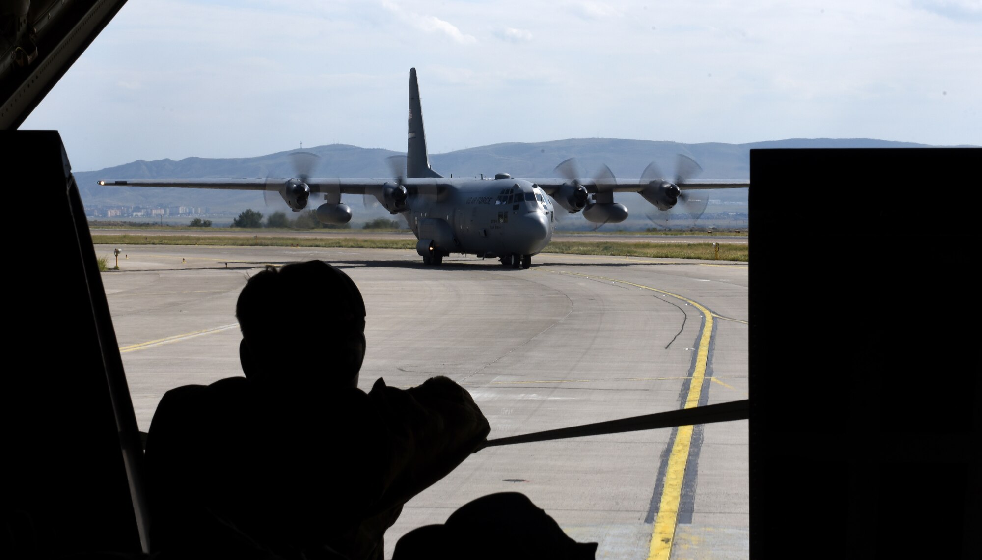 A U.S. Air Force flying crew chief from the 86th Aircraft Maintenance Squadron watches as a C-130H Hercules taxis in formation at Tbilisi International Airport, Georgia, Sept. 1, 2020.