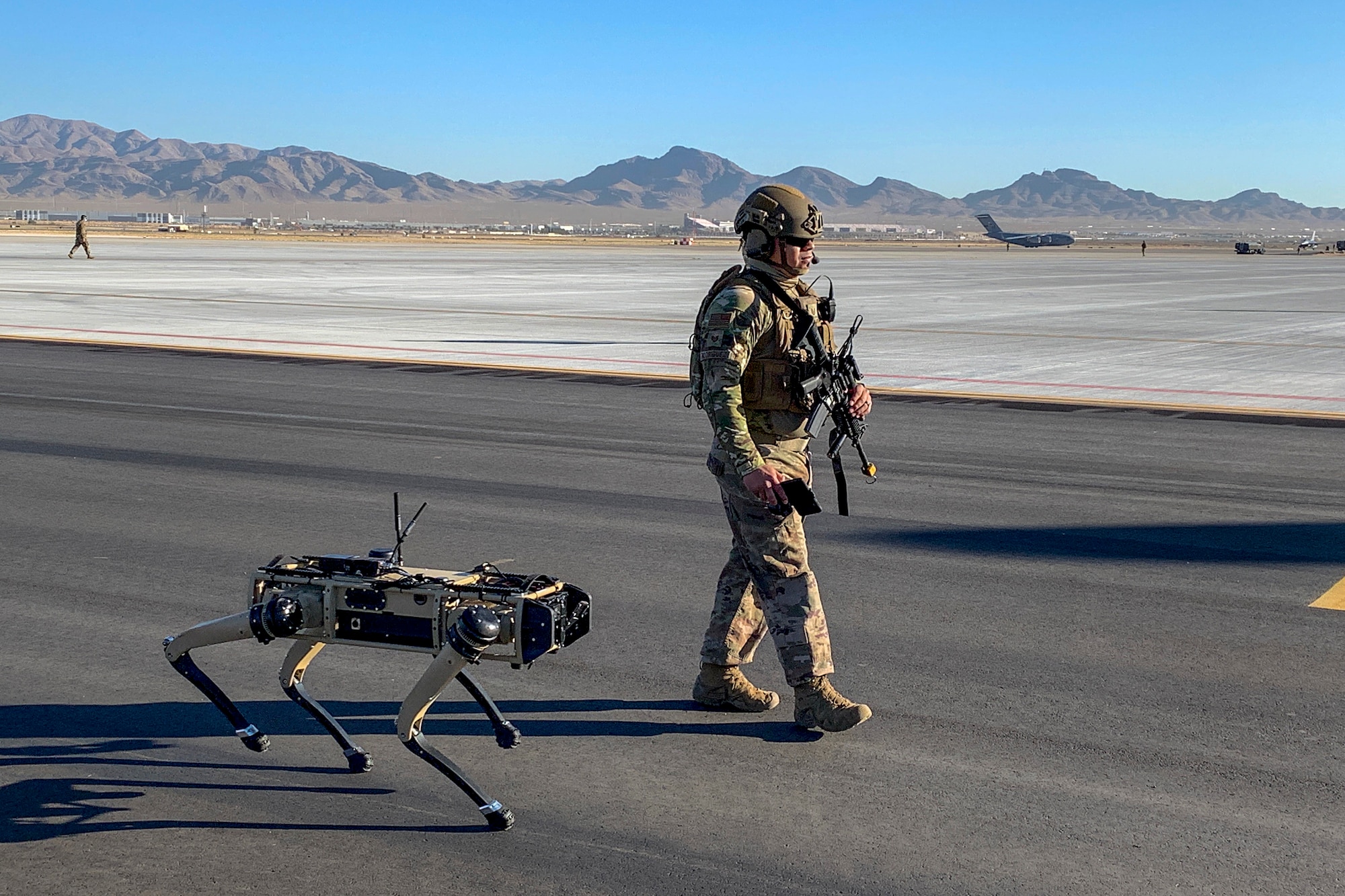 U.S. Air Force Tech. Sgt. Johnny Rodriguez, 321st Contingency Response Squadron force protection craftsman and lead defender for the CR team, walks with the robot dog during an agile combat employment exercise Sept. 3, 2020, at Nellis Air Force Base, Nevada. The robot dog is an experimental technology with the intent of aiding defenders to secure an airfield and is part of the Advance Battle Management System, which is being tested during ACE exercise. (Courtesy Photo)