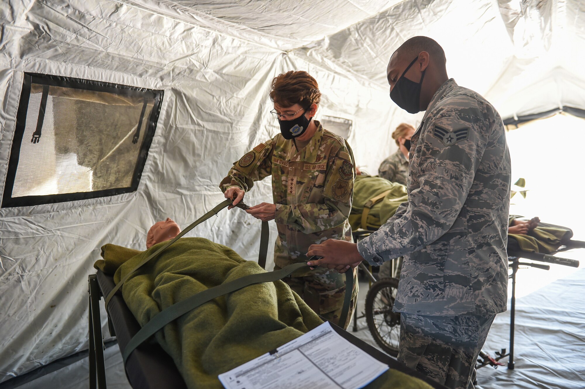 Gen. Jacqueline Van Ovost, Air Mobility Command commander, learns how to secure a patient to a litter from Senior Airman Dominique Springswoodley, 446th Aeromedical Staging Squadron medical technician, during her base tour at Joint Base Lewis-McChord, Wash., Sept. 3, 2020. The objective of the AMC leadership’s visit is to learn from and listen to AMC Airmen and their families. (U.S. Air Force photo by Airman 1st Class Mikayla Heineck)