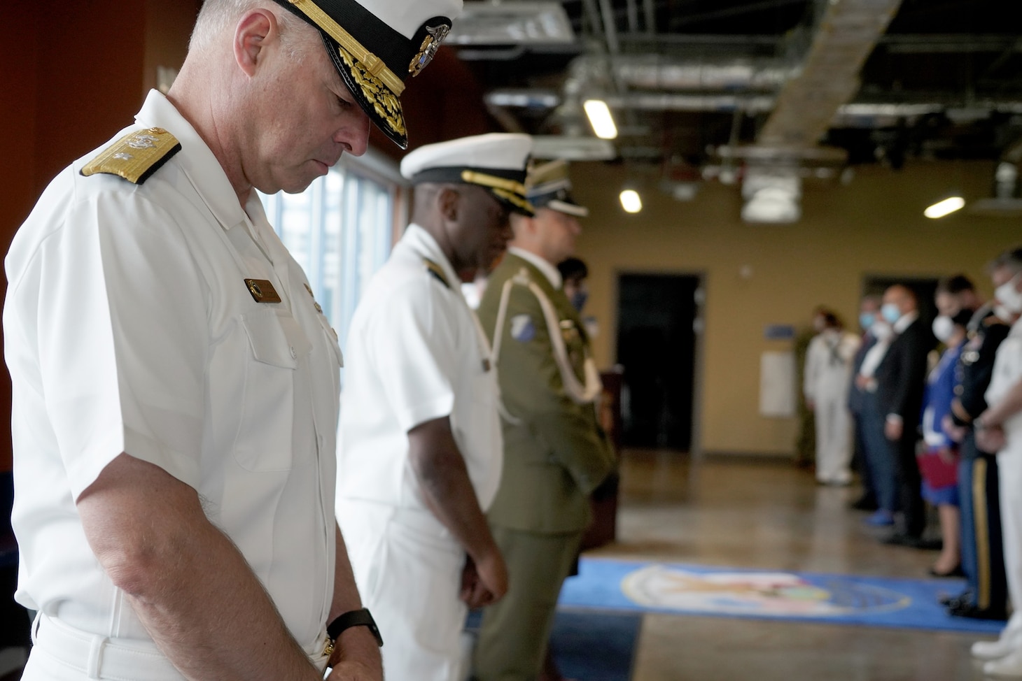 REDZIKOWO, Poland (Sept. 3, 2020) Rear Adm. Scott Gray, commander of Navy Region Europe, Africa, Central (EURAFCENT), and Capt. Eric Williams, commanding officer of Naval Support Facility (NSF) Redzikowo, join other dignitaries in observing the invocation at the commissioning ceremony for NSF Redzikowo, the Navy's newest shore installation. The event marked the official turnover of NSF Redzikowo's newly completed support facilities from the U.S. Army Corps of Engineers to the Navy. (U.S. Navy photo by Chief Master-At-Arms Sara E. Horvath/Released)