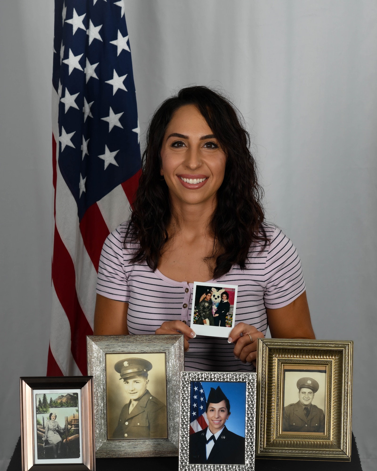 Senior Airman Christina Russo, a public affairs specialist with the 910th Airlift Wing, poses for a photo on Aug. 13, 2020, at Youngstown Air Reserve Station. The photos on display represent the military lineage within her family.