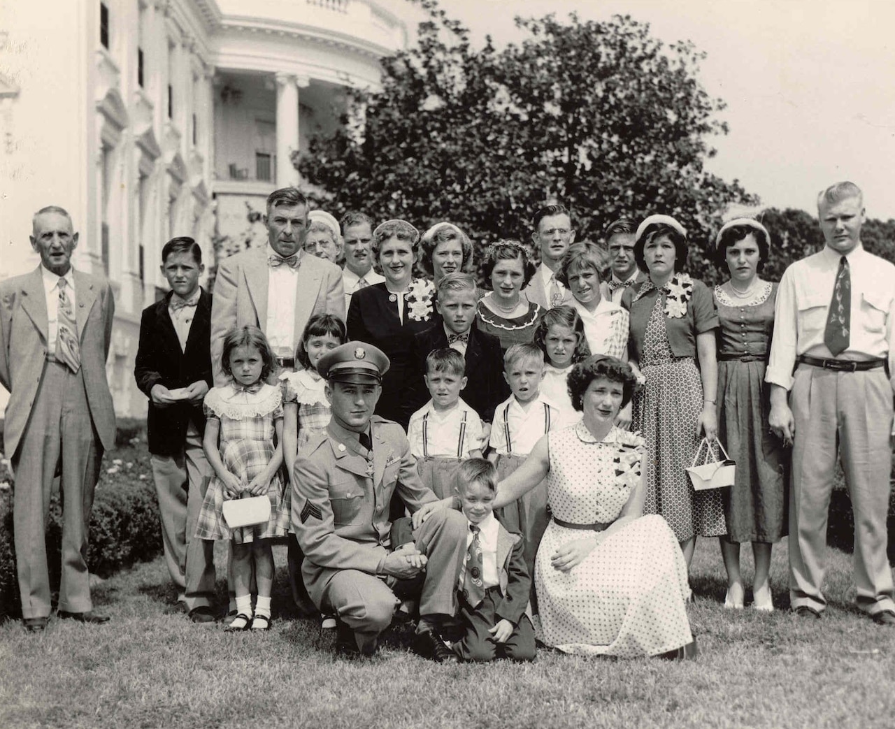 A large family poses on a lawn together.