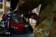 A photo of an Airman applying gear to a helmet