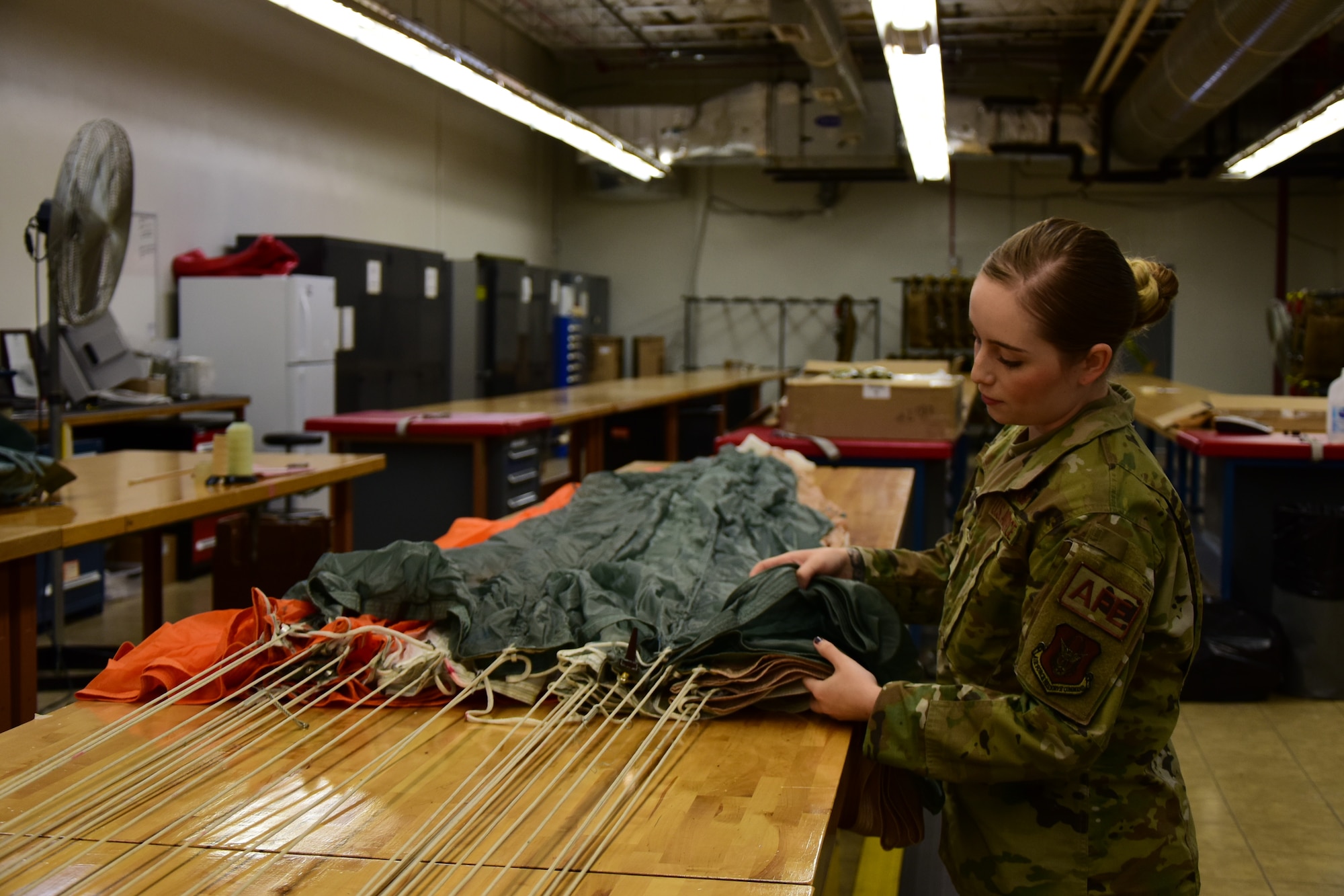 A photo of an Airman inspecting a parachute