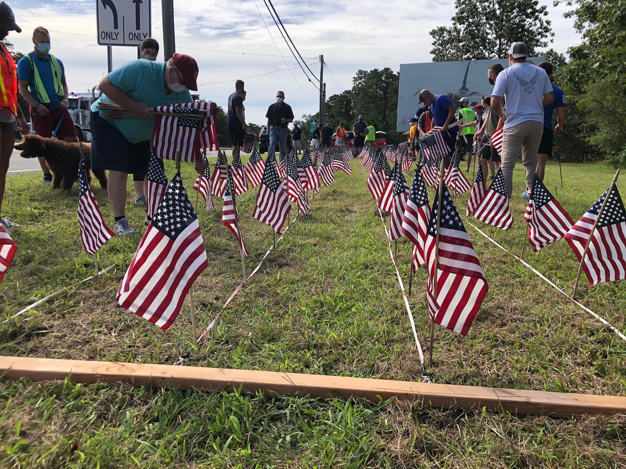 A photo of U.S. military veterans with the Flags for the Forgotten Soldiers organization, members of the Egg Harbor Township police department and members of the 177th Fighter Wing placing American flags in the ground.
