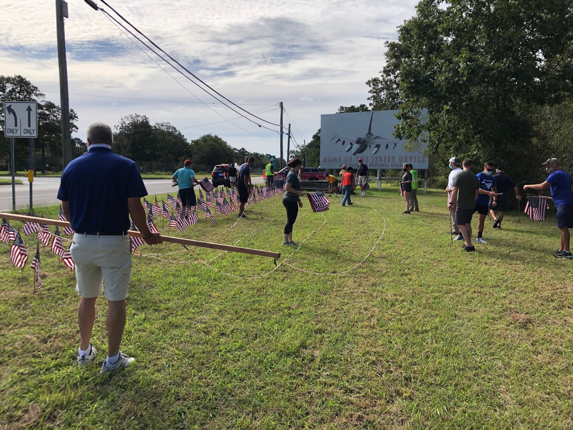 A photo of U.S. military veterans with the Flags for the Forgotten Soldiers organization, members of the Egg Harbor Township police department and members of the 177th Fighter Wing placing American flags in the ground.