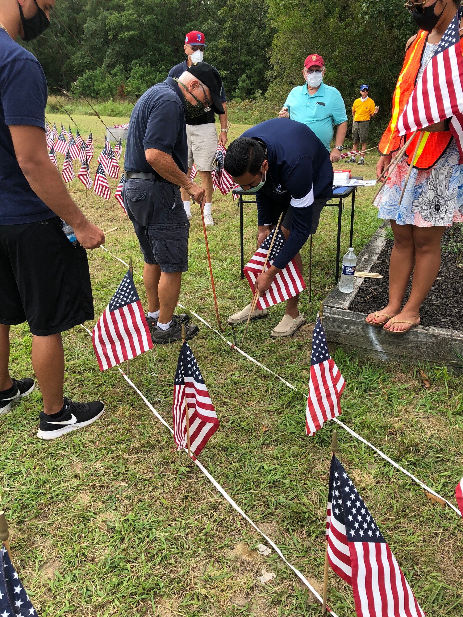 A photo of U.S. military veterans with the Flags for the Forgotten Soldiers organization, members of the Egg Harbor Township police department and members of the 177th Fighter Wing placing American flags in the ground.