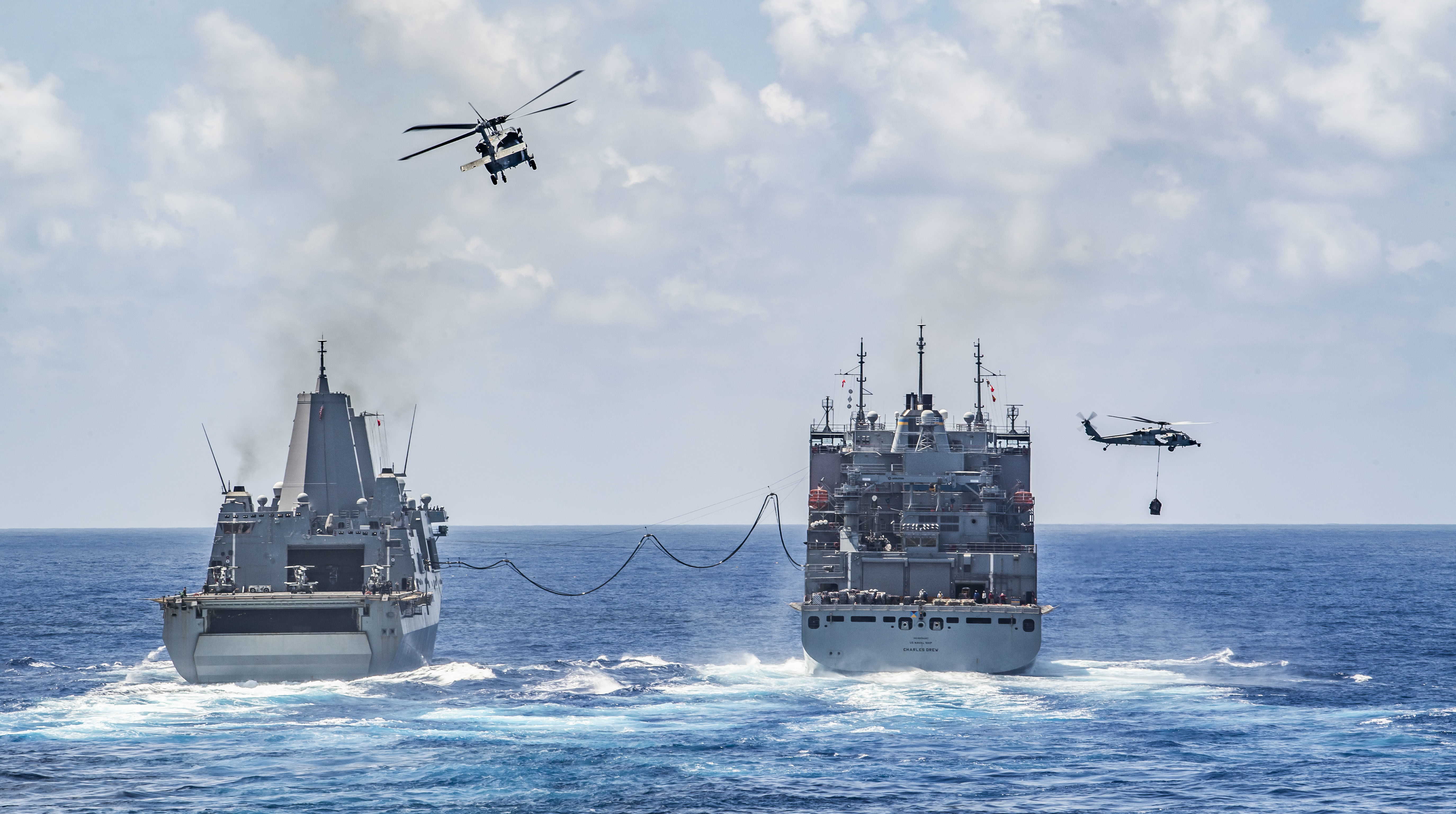 USS New Orleans (LPD 18), left, conducts a replenishment-at-sea with USNS Charles Drew (T-AKE 10) with MH-60S Sea Hawk helicopters.