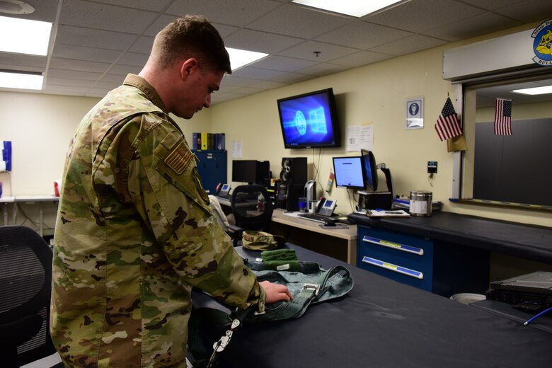 A photo of an Airman inspecting flight equipment