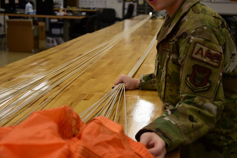 A photo of an Airman inspecting a parachute