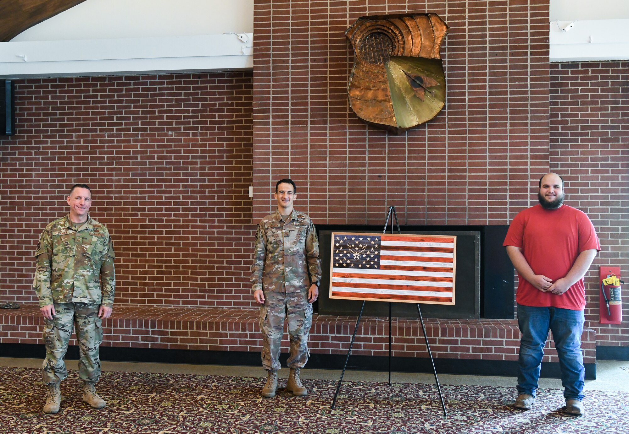 Arnold Engineering Development Complex (AEDC) Commander Col. Jeffrey Geraghty, center, and AEDC Superintendent Chief Master Sgt. Robert Heckman, left, accept on behalf of the Air Force a gift from Brandon Champion, an AEDC instrumentation technician, Aug. 7, 2020, at Arnold Lakeside Center at Arnold Air Force Base, Tenn. Champion gifted an artistic representation of a U.S. flag he made with wood to recognize the AEDC response to the COVID-19 pandemic. (U.S. Air Force photo by Jill Pickett)