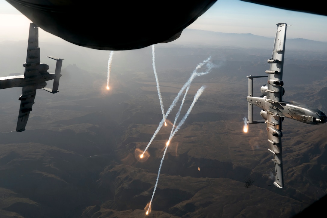 Two aircraft fly next to each other while leaving streaks in the sky.