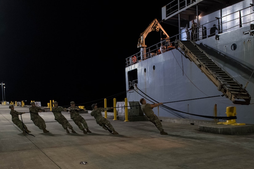 Soldiers pull the gangway into position for a ship.