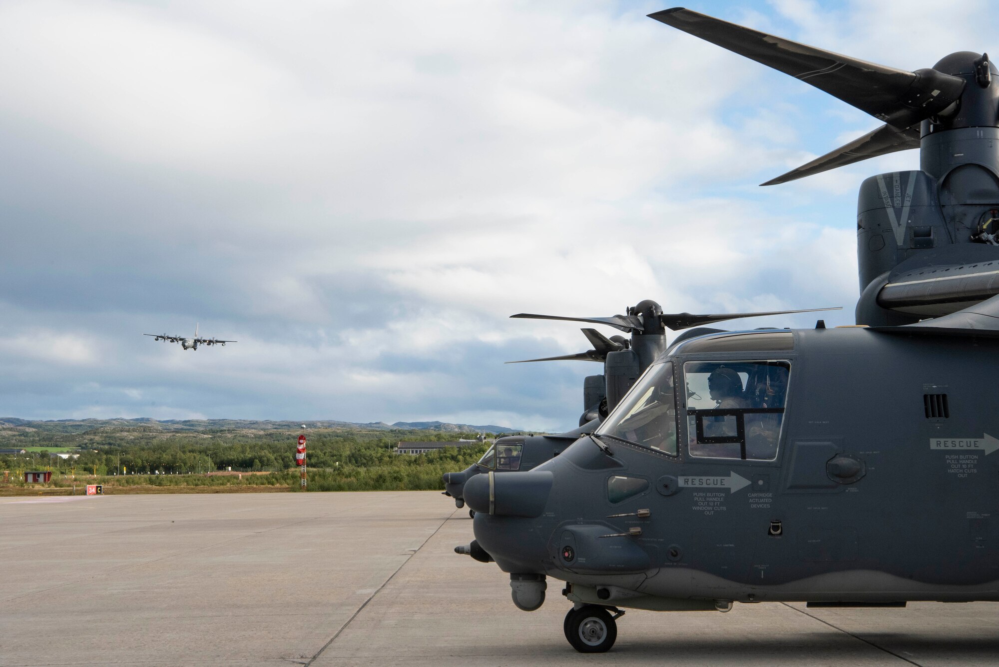 Two CV-22B Ospreys sit parked on a flight line as an MC-130J Commando II, all based out of RAF Mildenhall, U.K., prepares to land during a training exercise near Bodø, Norway, August 27, 2020. In-tegration with the Norwegian Air Force allowed the 352d Special Operations Wing to enhance and strengthen bonds with our partner nation and further secure the strategic high-north region. The exercise provided training for 352d Special Operations Wing members on capabilities such as personnel recov-ery, forward area refueling point, aerial refueling, maritime craft delivery system, and fast rope training. (U.S. Air Force photo by Staff Sgt. Michael Washburn)
