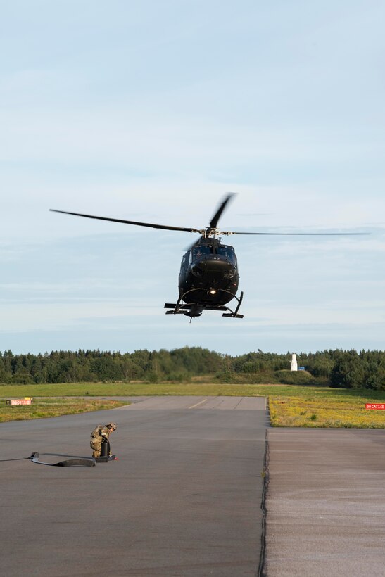 A Royal Norwegian Air Force Bell 412 helicopter hovers overhead of a 100th Logistics Readiness Squadron forward area refueling point specialist, during a FARP demonstration amid a training exercise at Rygge Air Station, Norway, August 26, 2020. Integration with the Norwegian Air Force allowed the 352d Special Operations Wing to enhance and strengthen bonds with our partner nation and further se-cure the strategic high-north region. The exercise provided training for 352d Special Operations Wing members on capabilities such as personnel recovery, forward area refueling point, aerial refueling, mari-time craft delivery system, and fast rope training. (U.S. Air Force photo by Staff Sgt. Michael Wash-burn)