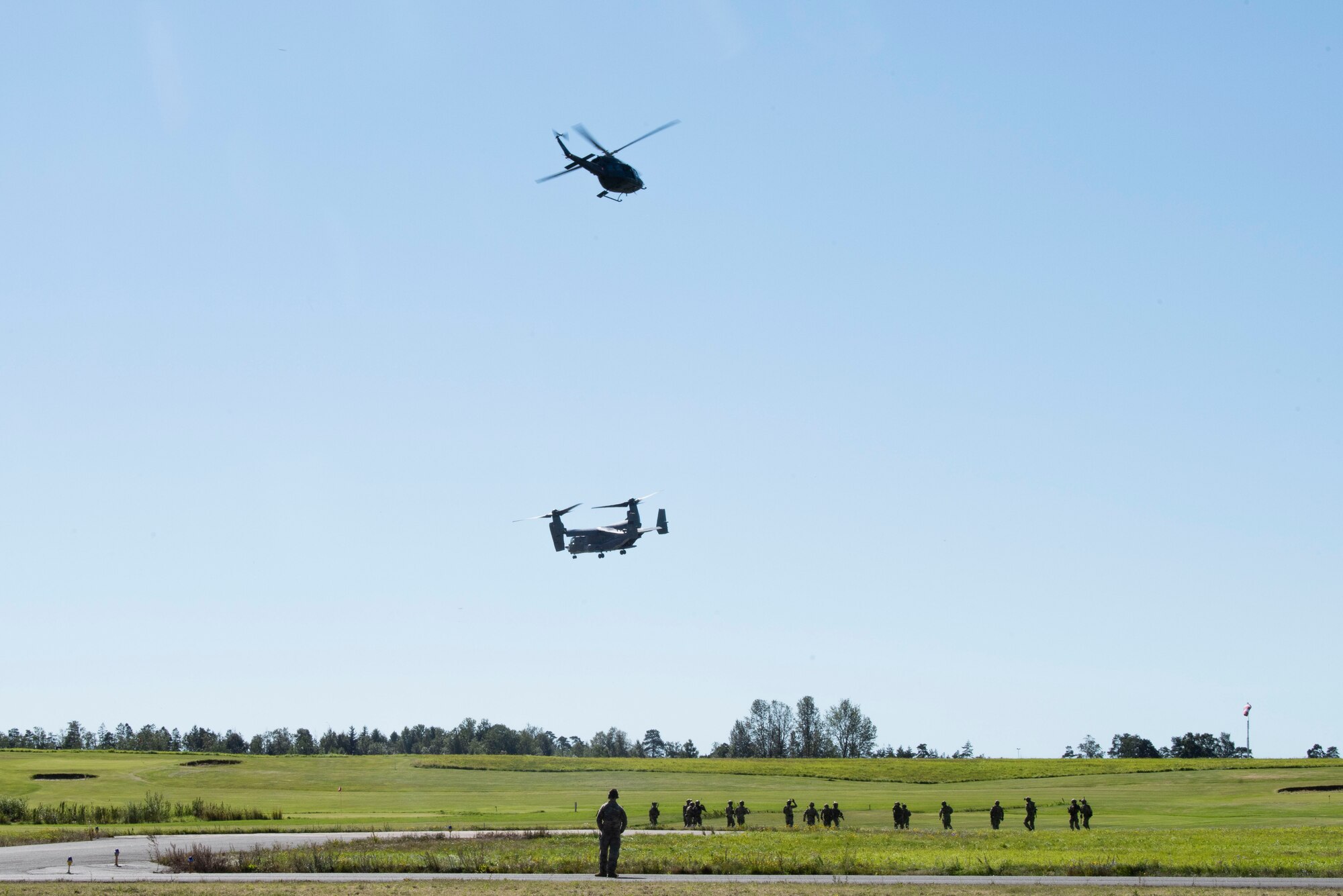 A Royal Norwegian Air Force Bell 412 Helicopter and a CV-22B Osprey, based out of RAF Milden-hall, U.K., hovers over 321st Special Tactics Squadron Airmen after performing fast-rope training at Rygge Air Station, Norway, August 25, 2020. Integration with the Norwegian Air Force allowed the 352d Special Operations Wing to enhance and strengthen bonds with our partner nation and further se-cure the strategic high-north region. The exercise provided training for 352d Special Operations Wing members on capabilities such as personnel recovery, forward area refueling point, aerial refueling, mari-time craft delivery system, and fast rope training. (U.S. Air Force photo by Staff Sgt. Michael Wash-burn)